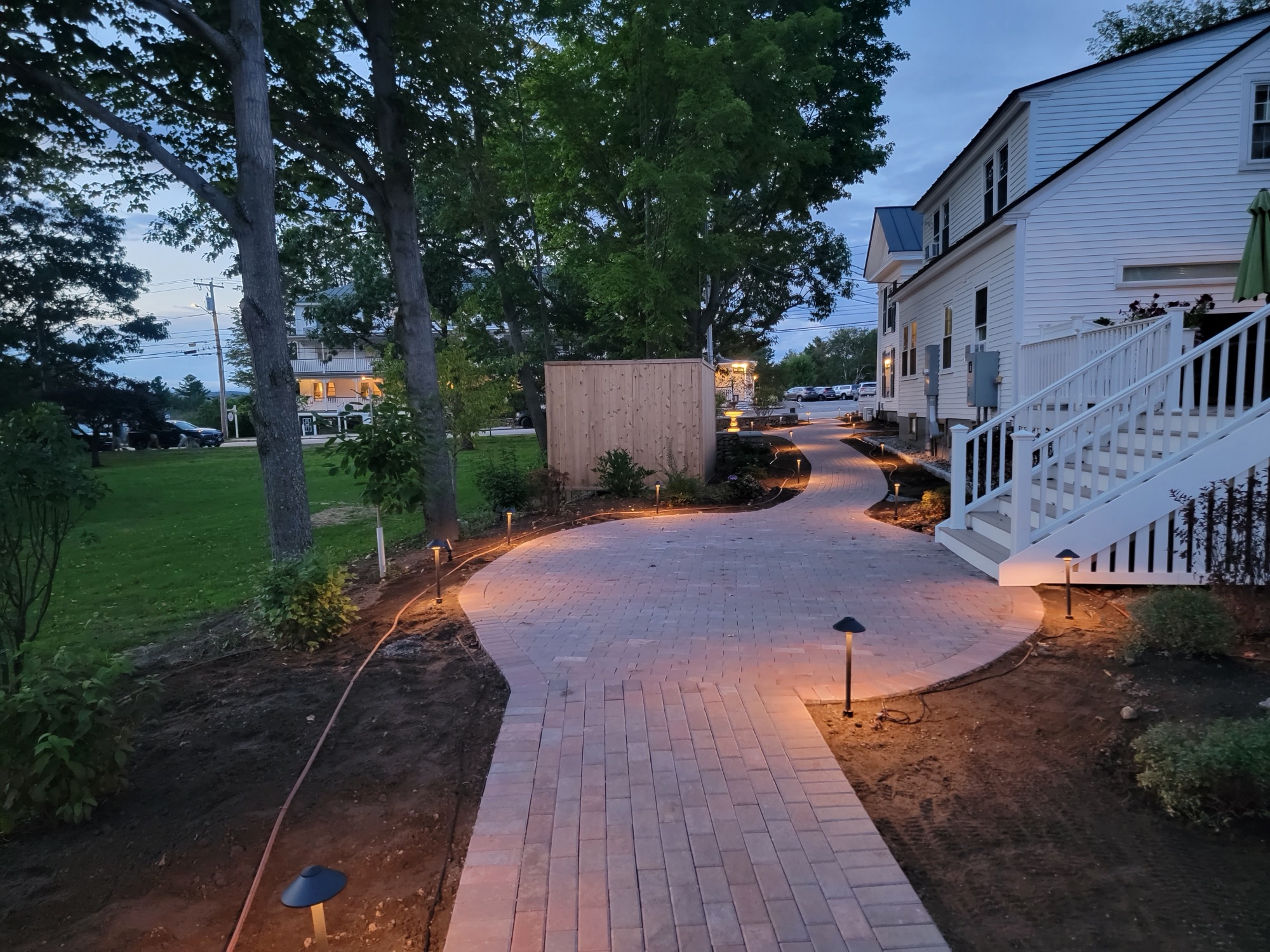 Brick walkway lit at dusk leading to a lakefront home