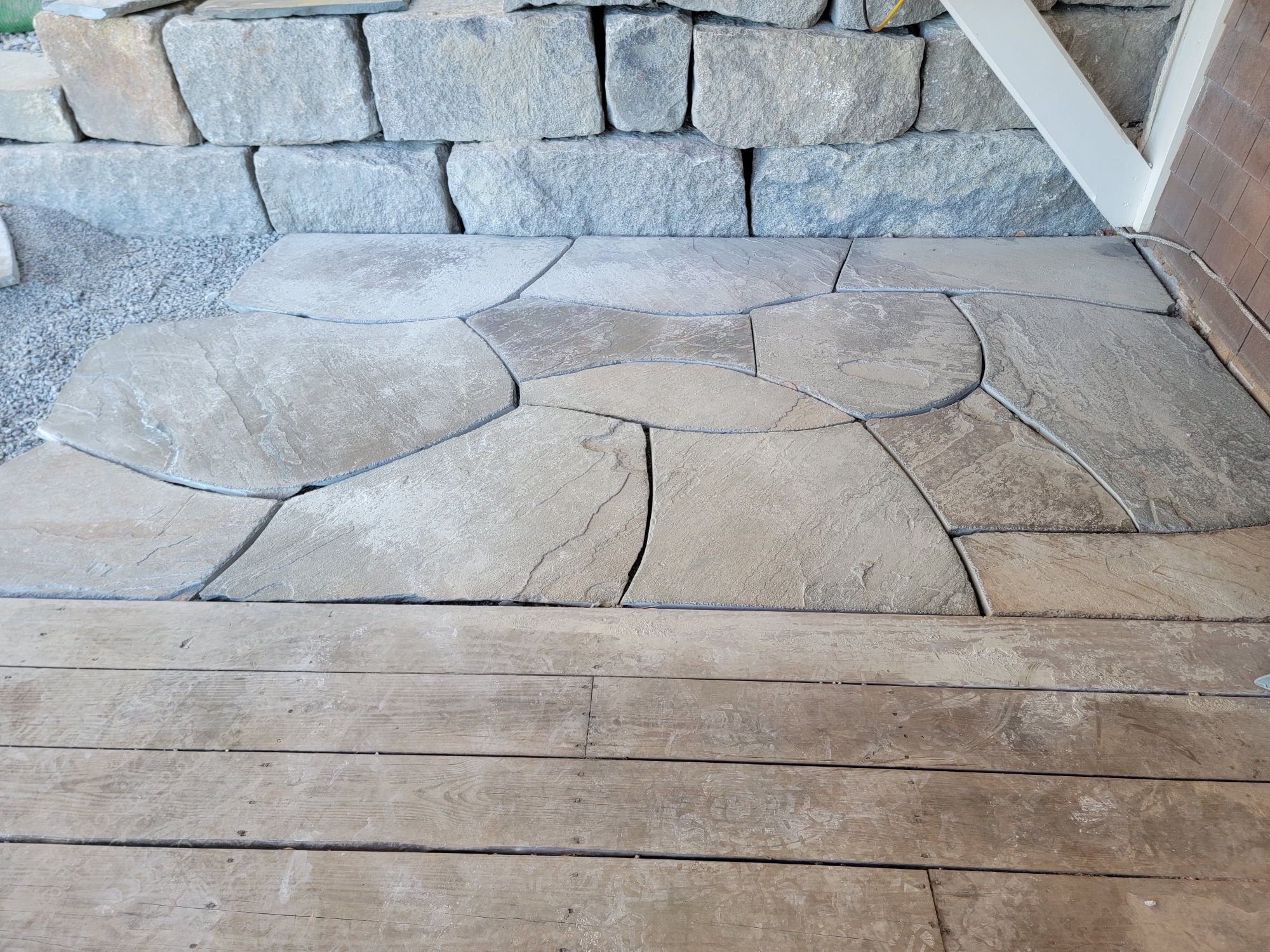 Flagstone landing meeting a stacked stone wall and wood deck